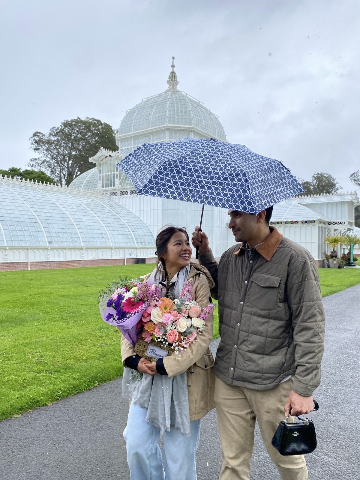Trinique holding flowers under Juan Pablo’s umbrella outside the Conservatory of Flowers