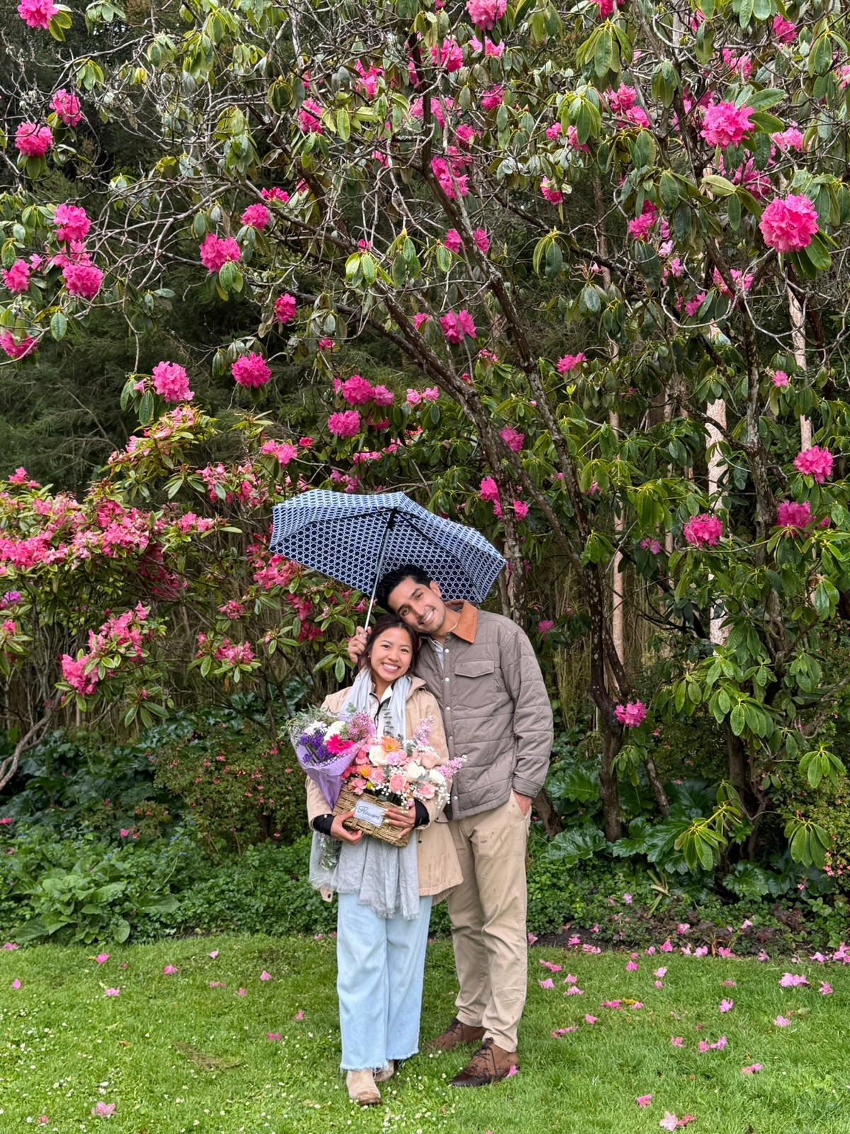 Trinique and Juan Pablo under an umbrella among pink rhododendrons
